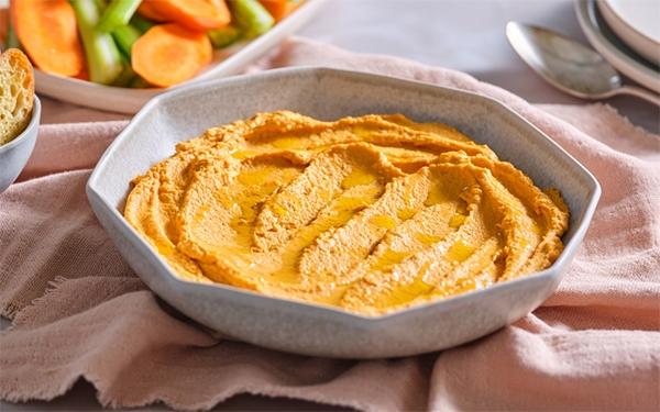 Roasted Red Pepper Hummus in a bowl with vegetables and crackers beside it