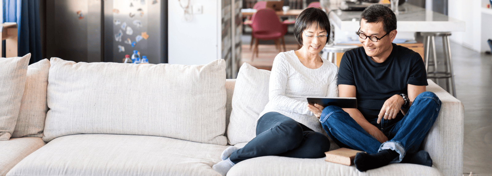Man and woman sitting on couch reading tablet