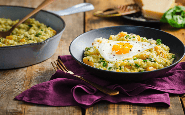 Creamy egg and squash risotto in a bowl with a fork
