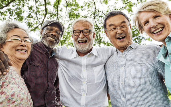 Group of diverse seniors smiling with arms around one another