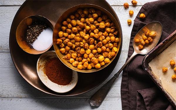 Roasted Chickpeas in a bowl with two smaller bowls beside it that contains salt, pepper and other spices