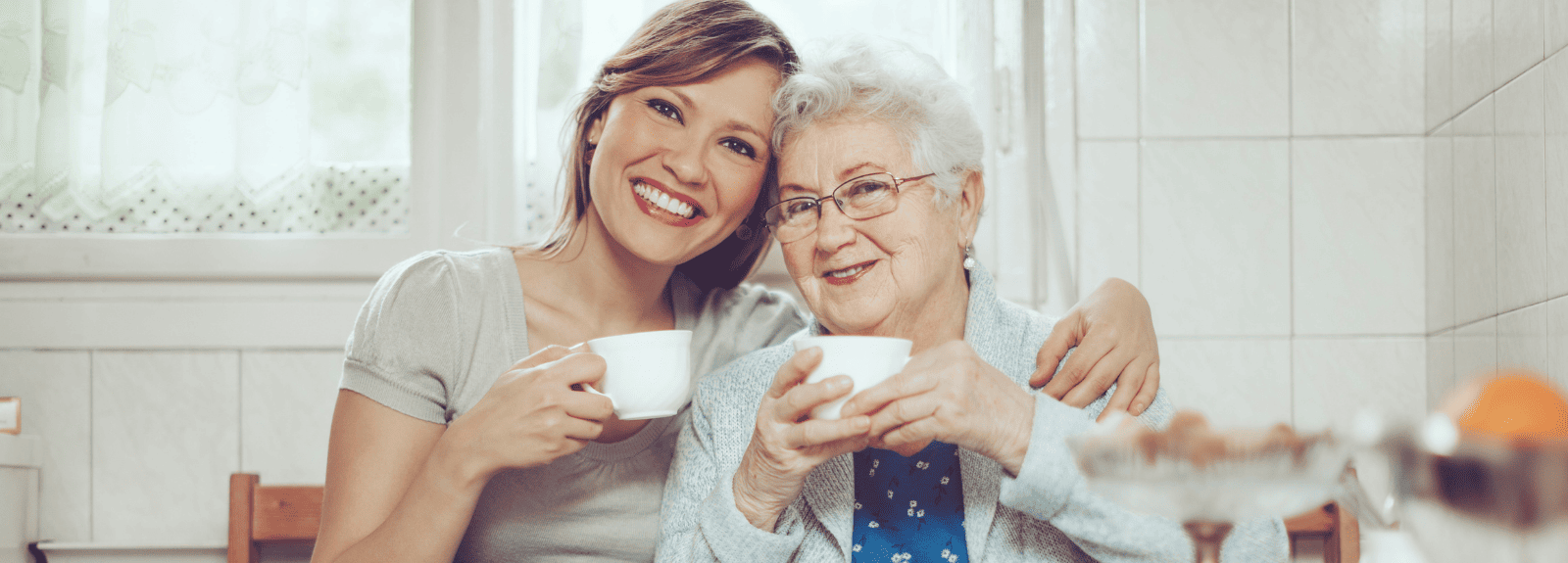 Une femme et une aînée sourient, une tasse de thé à la main.