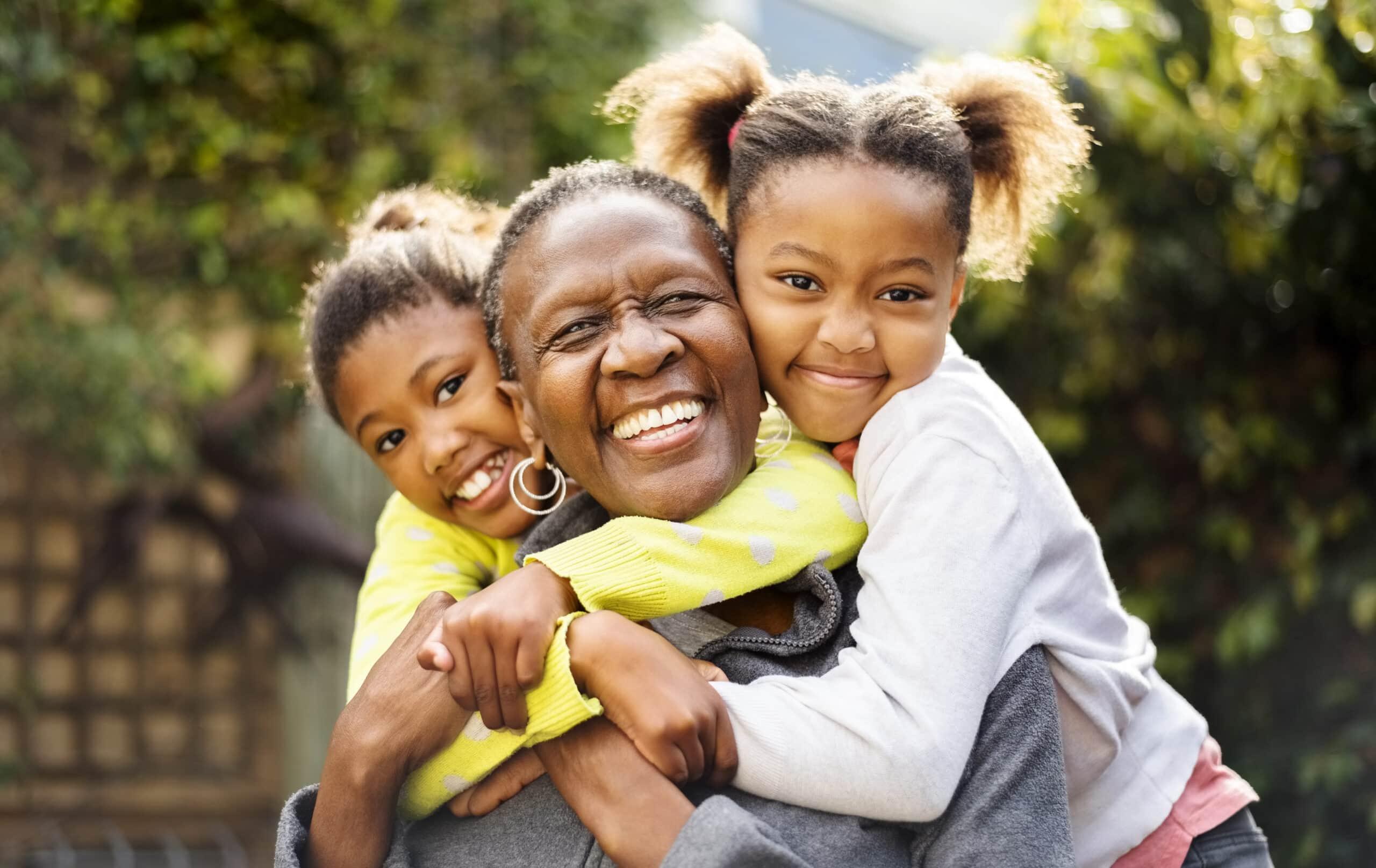 Senior woman cuddling her two granddaughters outdoors